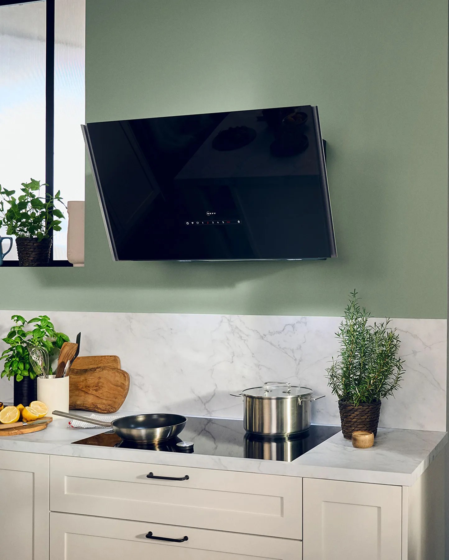 Neff angled cooker hood on a green kitchen wall