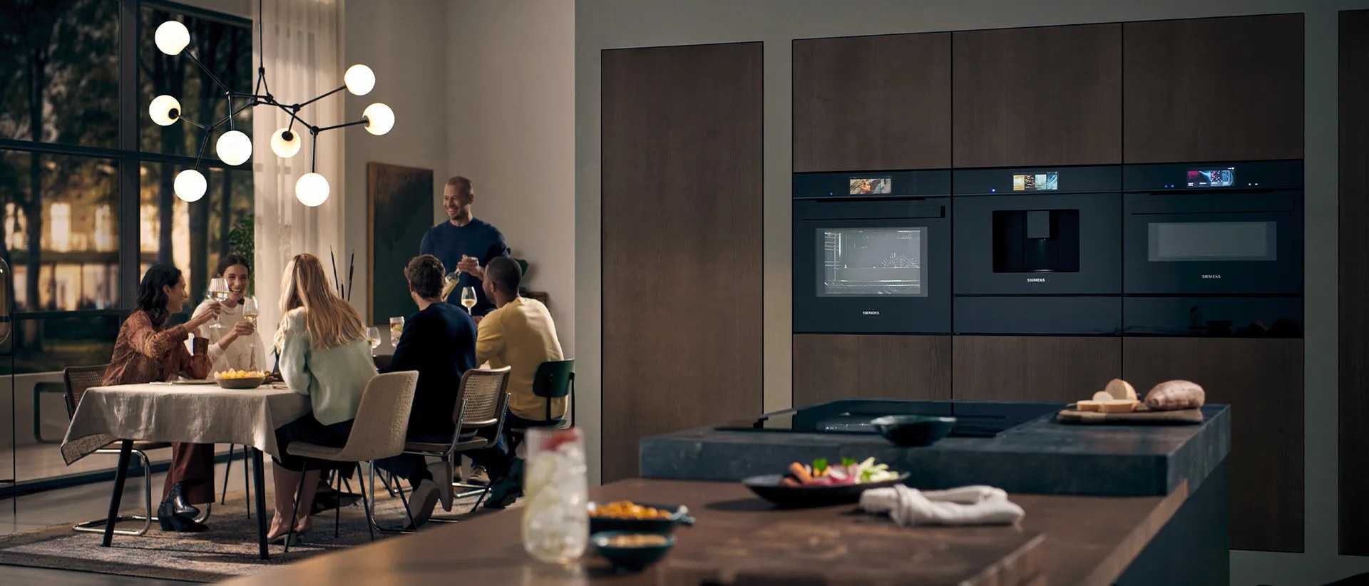 Siemens built-in ovens in a kitchen with people cooking