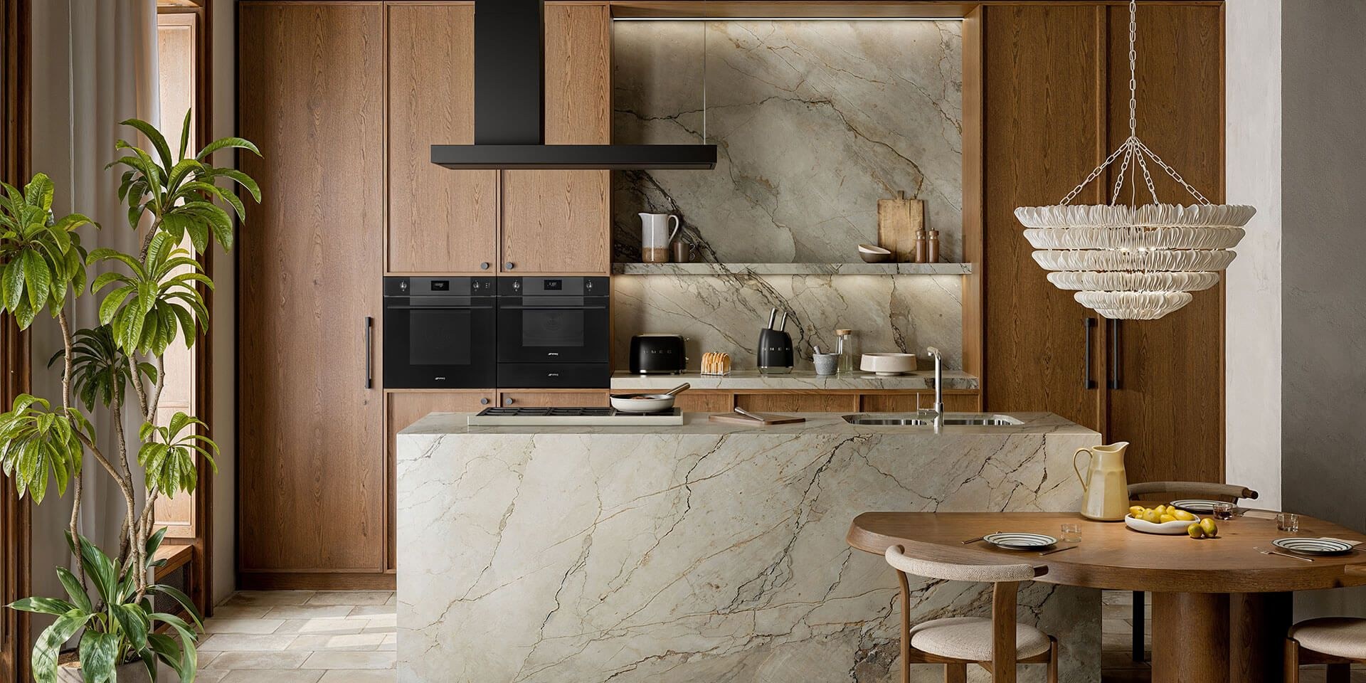 Kitchen with Smeg built-in oven and cooker hood above a marble island