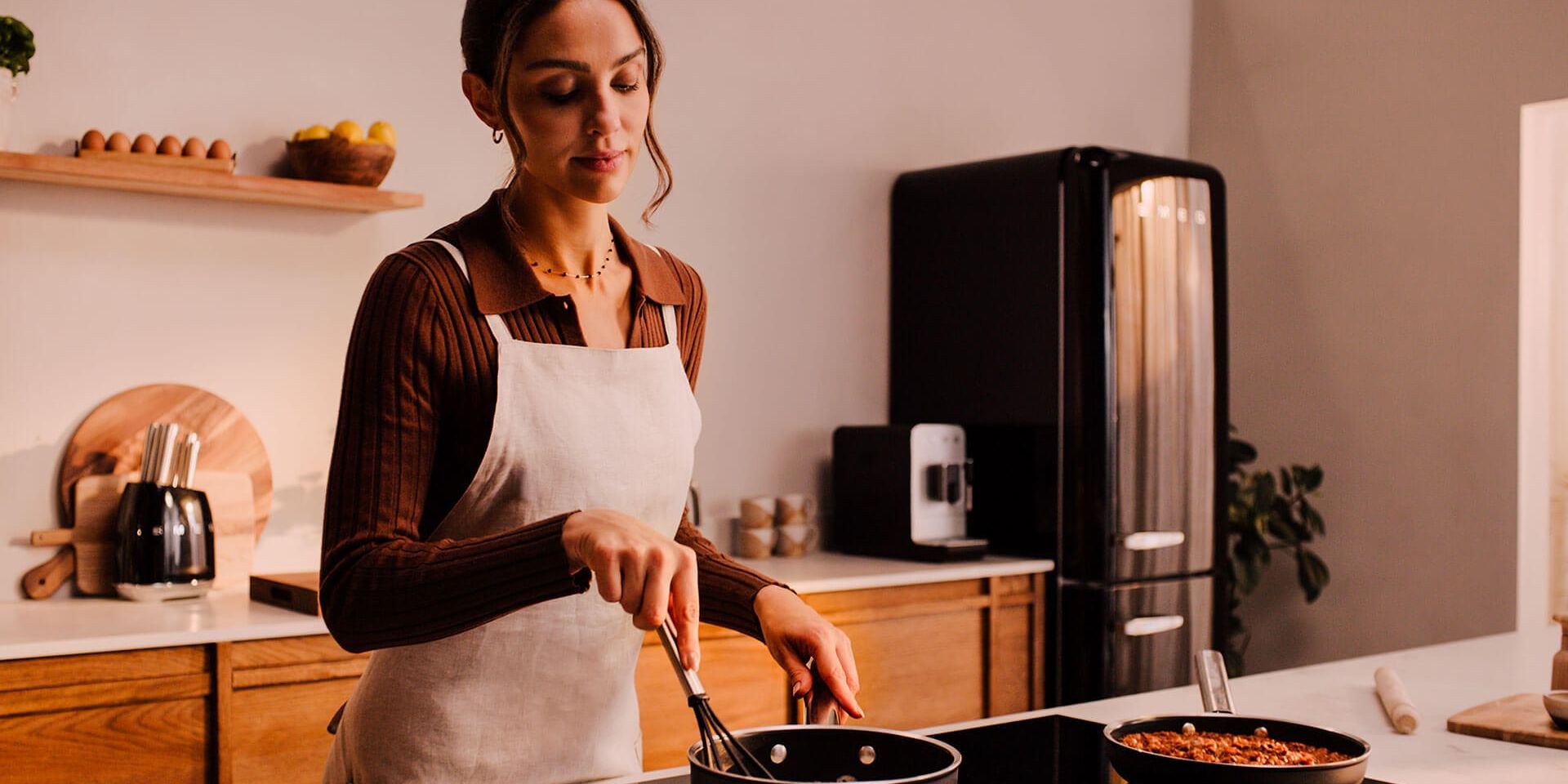Woman cooking in a kitchen with a Smeg fridge freezer